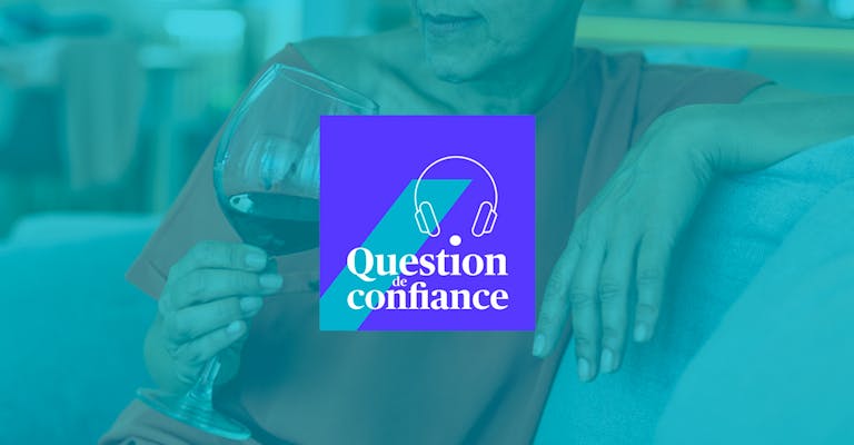 Gros plan sur les mains d'une femme assise dans un canapé tenant un verre à vin. Logo Question de confiance en surimpression.