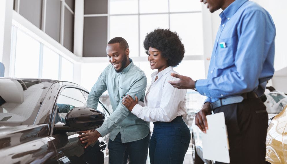 Directeur parle à un jeune couple montrant une nouvelle voiture