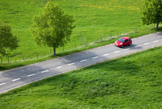 Petite voiture rouge conduit sur une route de campagne en vue aérienne