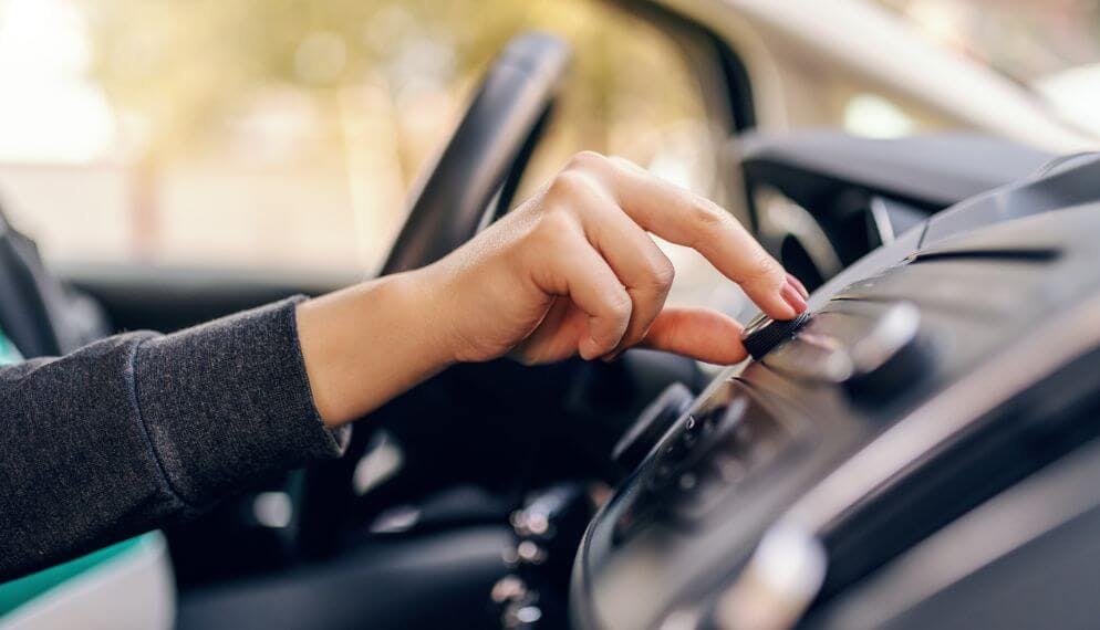 Un personne touche à sa radio dans sa voiture