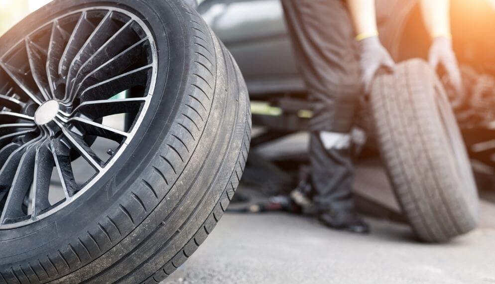 une personne en train de changer un pneu usé par un pneu neuf pour une voiture